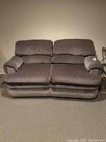 Front view of the double reclining chair with two seats and padded backrests and armrests in gray corduroy fabric.