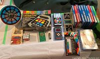 Wide image showing all items in the lot, including Fabulous Fred electronic game with box, Mini Match Me, Head to Head football game, Rubik's Cube with solution booklet, a few handheld electronic games, and Intellivision game cartridges.