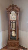 Full front view of oak-finish grandfather clock showing case design and proportions