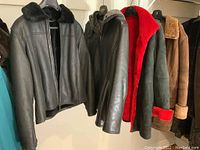 Four ladies leather and shearling coats and jackets hanging together, showing full views and variations in style and lining.