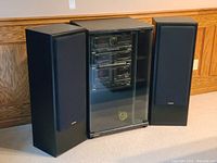 Fisher stereo system with two floor speakers and media stand on carpet