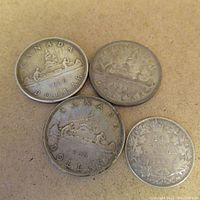 Four Canadian silver coins: three 1936 silver dollars and one 1931 half dollar on a flat surface.
