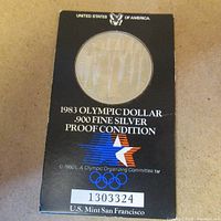 Photo of the front of the original display case showing 1983 Olympic dollar silver proof condition and serial number