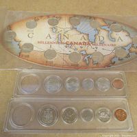 Two Canada Millennium 1999 coin sets in plastic holders with a map of Canada as background showing months and year 1999.