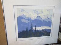 Framed print artwork showing landscape with pine trees and sky in shades of blue and green.