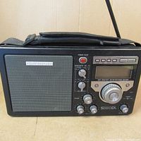 Front view of the Grundig S350 portable radio showing the speaker, control knobs, digital display, and antenna.