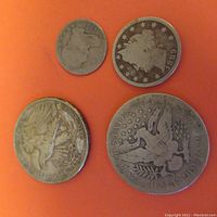 Four vintage U.S. coins displayed on an orange surface showing obverse and reverse sides of designs.