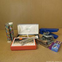 Photo showing entire lot of vintage office supplies and tubes of colorful bubble bath confetti on cardboard background.