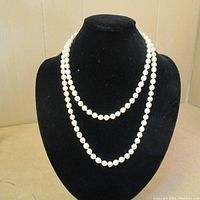 Full view of the double-strand white pearl necklace displayed on a black bust stand showing the necklace length and style