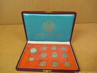 Full view of the Royal Thai Mint coin set inside a blue case with orange base displaying eleven coins of various sizes and denominations.