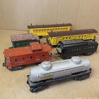 Overview of the full set of six vintage Lionel model train cars including caboose, tank car, coal car, and passenger cars.