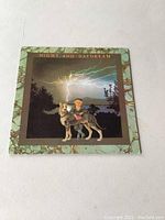 Photo of front cover of Night and Daydream LP album showing illustrated artwork of a child and dog with lightning in background, surrounded by a decorative marbled green border.