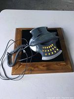 Photo showing the Batman phone handset and base shaped like the bat symbol with yellow keypad buttons and coiled cord.