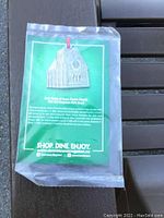 Front side of the pewter ornament in cellophane packaging with green background card providing church description.