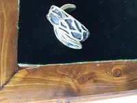 Close-up of single earring showing lattice cutout design and curved crescent shape.