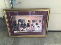 Photo showing the gold framed wedding day print leaning against a wall, includes reflection of a light fixture on the glass surface.