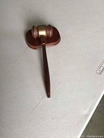 Wooden gavel resting on oval wooden block with feet on a flat surface