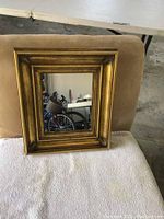 Front angled view of gold framed vintage mirror showing the frame thickness and clarity of mirror glass.