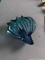 Top and angled view of aqua blue Murano glass bowls shaped like a seashell, showing gloss, transparency and ribbed texture mimicking natural sea shell form.