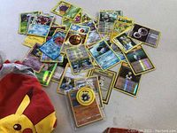 Scattered assortment of Pokémon trading cards previewing various cards including holographic and Trainer cards.