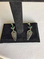Front view of both earrings displayed on black velvet stand, showing green malachite stones and etched pewter details