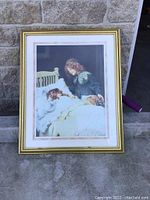 Framed art print showing two girls and a dog lying on a bed within a gold frame