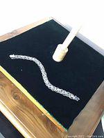 Full view of sterling silver filigree charm bracelet laid flat on black velvet display, showing chain links and clasp.