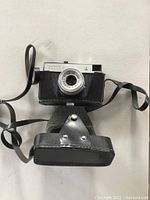 CMEHA Smena 8M vintage 35mm film camera in black leather carrying case with shoulder strap. Camera and case show wear and age.