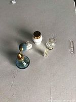 View of all 5 vintage perfume bottles on a gray surface, showing size and shape variety