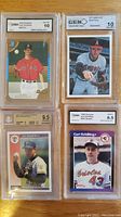 Top front view of four graded baseball cards by GMA and GEM: Nolan Ryan SSPC 1975, Curt Schilling 1989 Donruss rookie, Tim Wakefield 1992 Score rookie, and Clay Buchholz 2005 Bowman rookie.