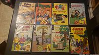 Image showing the 8 comics including Prince Valiant, Popeye, Tiger, Quincy, Beetle Bailey, Blondie, and The Phantom. Comics placed flat on a dark surface, each in protective plastic sleeves.