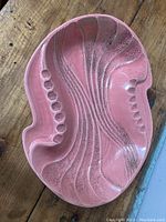Overhead view of the large pink and gold ashtray showing abstract grooves and cigarette rests.