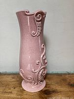 Large pink ceramic vase with raised scroll details, front and side views showing its shape and decoration.