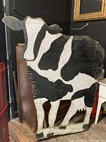 Full view of the large wooden cow garden decor showing its distinct black and white pattern and shape.