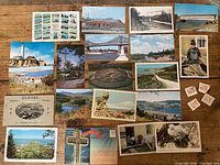 Photo showing vintage postcards with color and black-and-white Canadian landscapes, buildings, and landmarks arranged on a wooden surface.