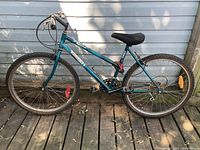 Side view of blue Triumph Versail DX mountain bike showing full frame, tires, seat, handlebar, chain, and reflectors.