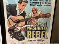 Framed 1966 Nashville Rebel movie poster showing main artwork, characters with guitar and bed scene, title, and car chase scene.