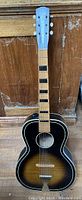 Full front view of the vintage acoustic guitar showing the sunburst finish and block inlay fretboard.