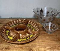 Photo showing all three snack dishes arranged on wooden surface: large segmented ceramic dish and two leaf-patterned glass bowls