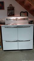 Front view showing full vintage General Electric kitchen range with four coil burners and double oven doors, white porcelain finish, chrome accents.