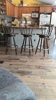 Three wooden bar stools lined up in front of a kitchen counter