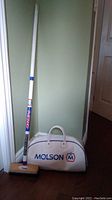 Full lot showing the Iceman II 8-Ender curling broom propped against the wall with vintage Molson gym bag