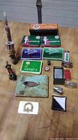 Full collection of smoking related items laid out including pipe, tobacco tins, lighters, and accessories