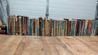 Long row of 60 vintage paperback sci-fi books showing spines with colorful titles and authors, arranged on wood surface