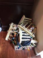 Two vintage style plastic window candelabras with colored bulb-shaped lights, tangled string lights and cords piled on floor.