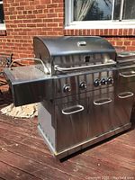 Front view of grill with lid closed showing control panel, knobs and cabinet doors