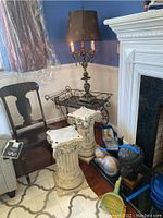Wide shot showing entire lamp with shade, metal cart, pedestals and some additional items on floor near fireplace.