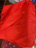 Red fabric tablecloth with subtle pattern folded on a wooden surface.