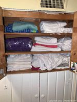 Full view of wooden cabinet shelves filled with folded towels of various colors and sizes.