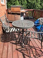 Photo showing round metal patio table with lattice top and one matching chair with armrests